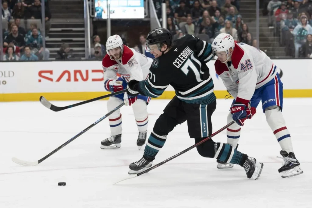 San Jose Sharks center Macklin Celebrini (71) shoots the puck during the second period against Montreal Canadiens defenseman Noah Dobson (53) and Montreal Canadiens defenseman Lane Hutson (48) at SAP Center at San Jose.
