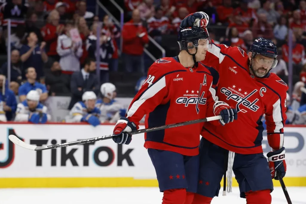 Washington Capitals defenseman John Carlson (74) is congratulated by Capitals left wing Alex Ovechkin (8) while being recognized for his 1,100th NHL point during a timeout against the St. Louis Blues during the first period at Capital One Arena.