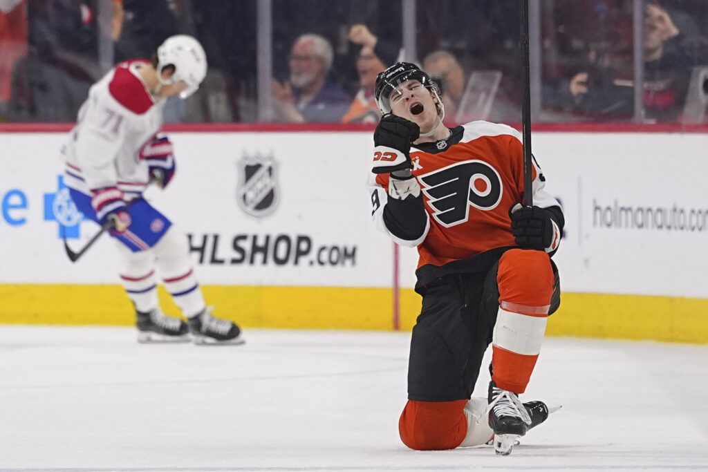 Flyers' Oliver Bonk celebrates on one knee on the ice while a Canadiens player in the background looks down at his feet.