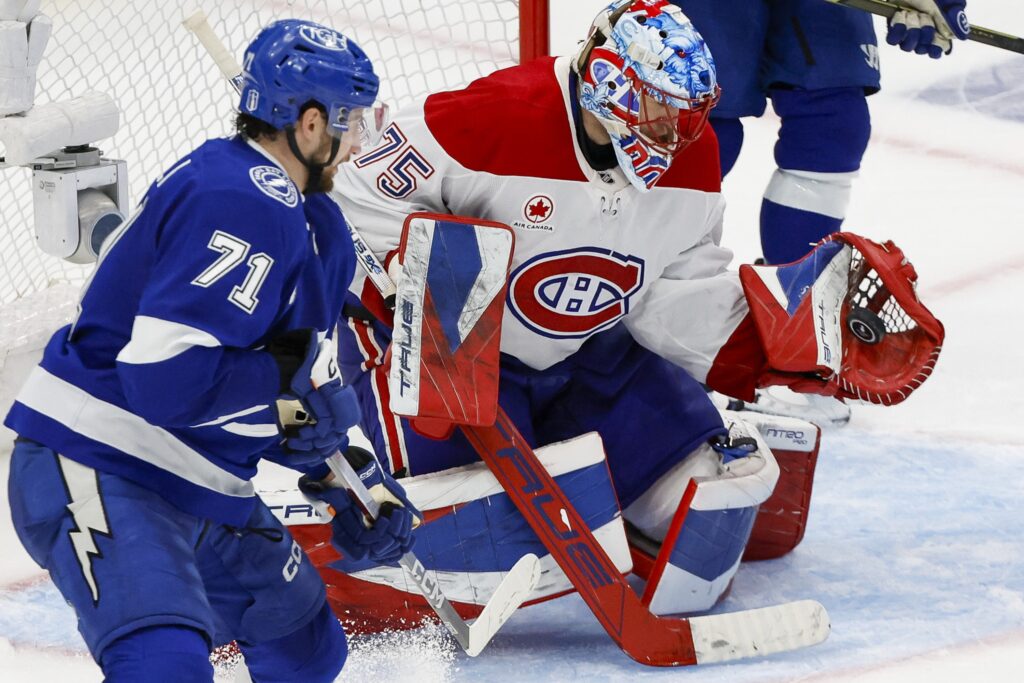 The puck is in Jakub Dobes's glove as Lightning's Anthony Cirelli looks on.