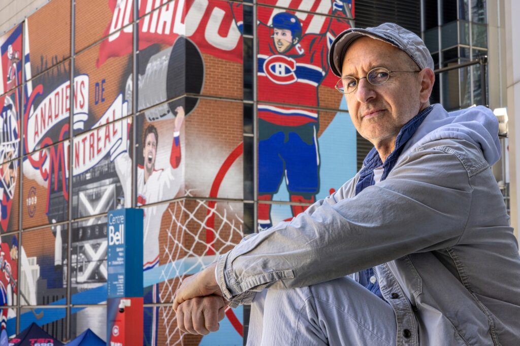 Oren Safdie sits outside with a Bell Centre mural of Canadiens players in the background.