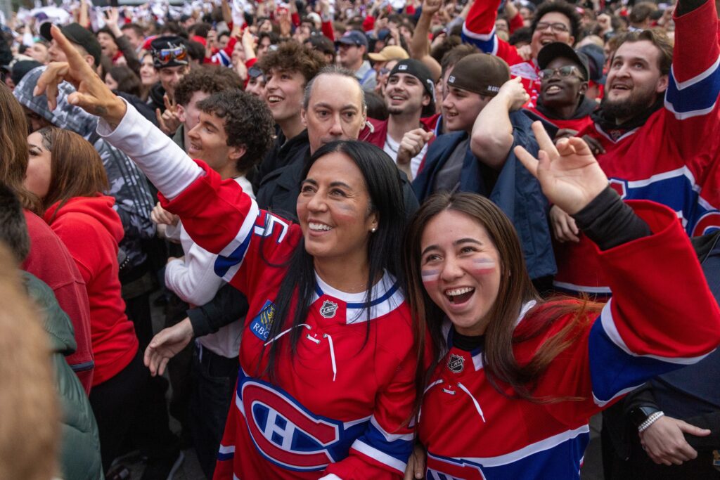Soraya Martinez Ferrada and a young girl, both in Canadiens jerseys, smile and cheer among a crowd of people outside.
