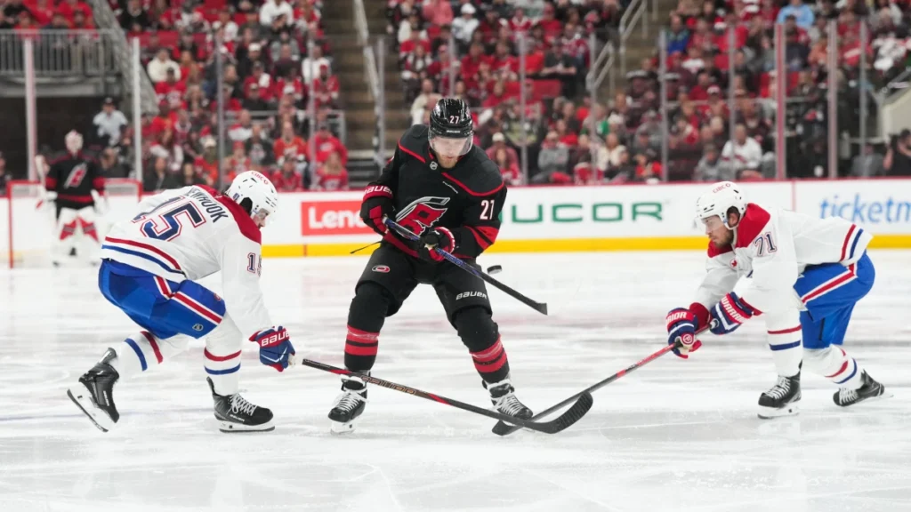 Carolina Hurricanes left wing Nikolaj Ehlers (27) passes the puck as Montr&eacute;al Canadiens center Alex Newhook (15) and Montr&eacute;al Canadiens center Jake Evans (71) defend during the third period in game two of the Eastern Conferene Final of the 2026 Stanley Cup Playoffs at Lenovo Center.