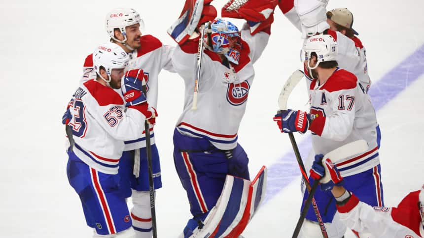Five hockey players wave their arms to celebrate their victory on an ice rink.