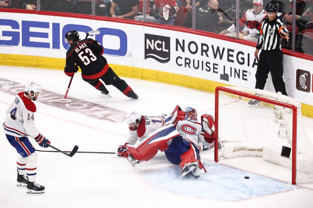 Hockey player scores a goal past a goalie sprawled on his back.