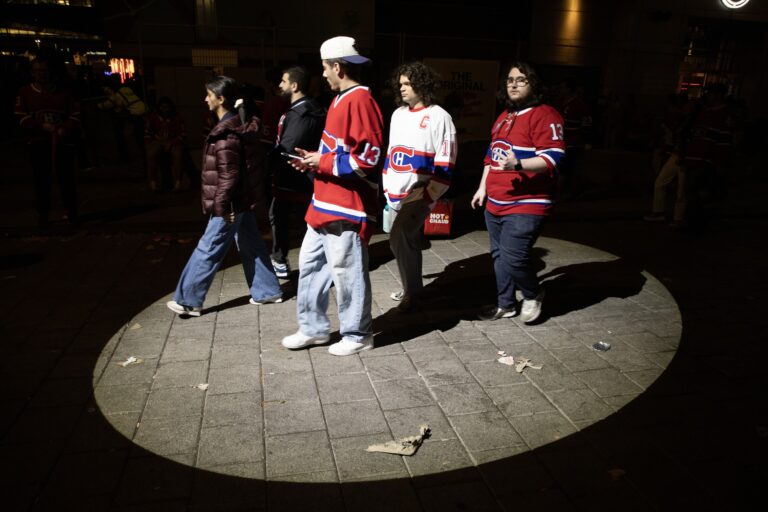 Five Canadiens fans walk through an illuminated circle of pavement at night.