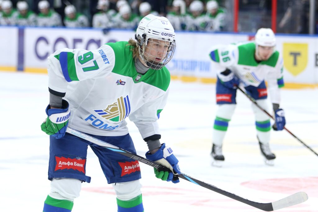 Close-up of Alexander Zharovsky wearing a white jersey with green trim on the ice during a KHL game.