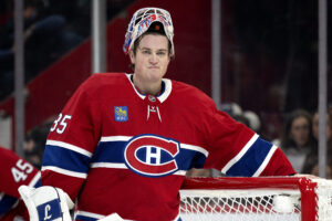 Samuel Montembeault stands in front of his net with his mask up and an unhappy look on his face.