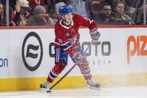 Canadiens winger Cole Caufield is seen near the boards in the offensive zone with the puck on his stick as he is about to pass.
