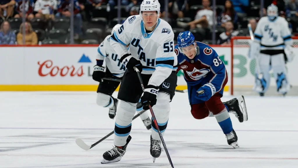 Utah Mammoth defenseman Maksymilian Szuber (55) controls the puck ahead of Colorado Avalanche center Nikita Prishchepov (85) in the third period at Ball Arena.