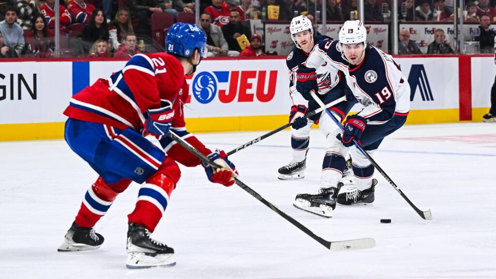 Nov 16, 2024; Montreal, Quebec, CAN; Columbus Blue Jackets center Adam Fantilli (19) plays the puck against Montreal Canadiens defenseman Kaiden Guhle (21)  during the third period at Bell Centre. Mandatory Credit: David Kirouac-Imagn Images