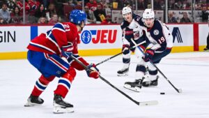 Nov 16, 2024; Montreal, Quebec, CAN; Columbus Blue Jackets center Adam Fantilli (19) plays the puck against Montreal Canadiens defenseman Kaiden Guhle (21)  during the third period at Bell Centre. Mandatory Credit: David Kirouac-Imagn Images