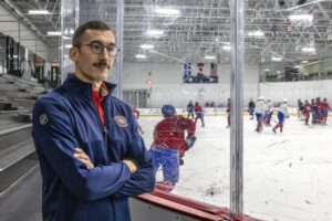 Rocket head coach Daniel Jacob seen outside the boards at Canadiens' practice facility in Brossard as players practice on the ice behind him.