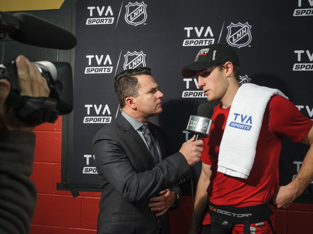 A TVA Sports journalist interviews a player with a TVA Sports towel on his shoulder.